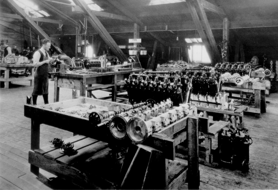 Roméo Vachon travaillant au banc dans lâatelier de la Laurentide Air Services (vers 1922). La plupart des moteurs figurant sur la photo sont des Curtiss HS-2L de type Liberty, de 12 cylindres.